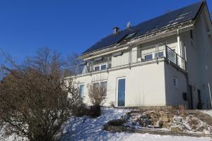 a white house with a black roof in the snow at Ferienwohnung Doris in Schmalkalden