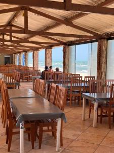 a restaurant with tables and chairs with the ocean in the background at Juscelino Pousada lazer in Tibau