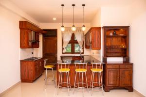 a kitchen with wooden cabinets and a bar with stools at Windsor Crest in Kandy