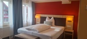 ein Schlafzimmer mit einem weißen Bett und einer roten Wand in der Unterkunft Hotel Pflug in Dornhan