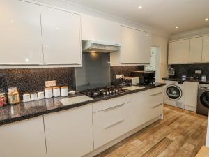 a kitchen with white cabinets and a stove top oven at Red Brick Haven in East Cowes