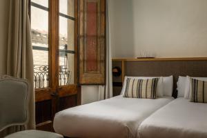 a bedroom with two beds and a window with a balcony at BYPILLOW Cluc Begur in Begur