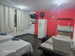 a room with a red wall and a refrigerator at Pousada do Luquinhas in Brasília