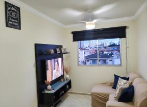 a living room with a couch and a television at Apto 2Q Centro Wifi Shopping Garage in Taubaté