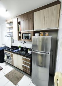 a kitchen with wooden cabinets and a stainless steel refrigerator at Apto 2Q Centro Wifi Shopping Garage in Taubaté