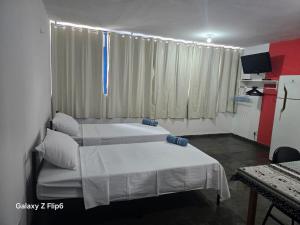 a bedroom with two beds and a television in it at Pousada do Luquinhas in Brasília