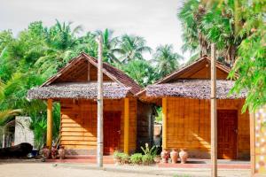 a small wooden house with palm trees in the background at Beach View Resort in Batticaloa