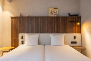 a bedroom with a white bed with a wooden headboard at Postillion Utrecht Bunnik in Bunnik