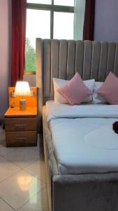 a bedroom with a bed and a lamp and a window at Zion Crest Suites - Kilimanjaro Helichrysum Homes in Arusha