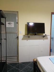 a flat screen tv on a wall next to a door at Casa três com cozinha americana in Araruama