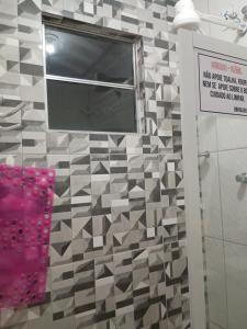 a bathroom with a window and a tiled wall at Casa três com cozinha americana in Araruama +17 photos