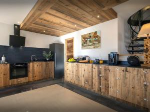 a kitchen with wooden cabinets and a black appliance at Chalet Paralpin - OVO Network in Manigod