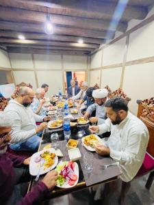 a group of people sitting around a table eating food at Zimsa Resort Skardu in Skardu