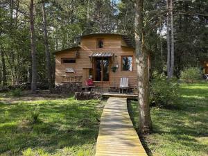 a log cabin in the woods with a walkway leading to it at Domaine de la Mamounette in Champclause