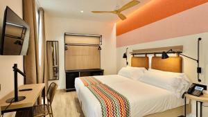 a bedroom with a bed and a desk and a television at Hotel Doho in Málaga