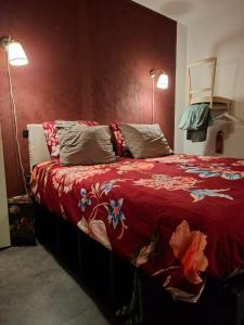 a bedroom with a bed with a red blanket and two lamps at B&B Biej' oons tuus in Hellendoorn