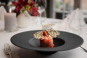 a plate of food with a strawberry on a table at Romantik Hotel Schweizerhof in Grindelwald +69 photos