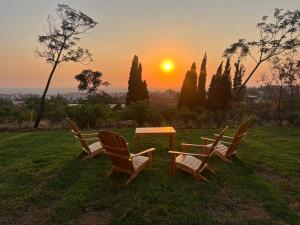 three chairs and a table with a sunset in the background at Dusk batroun in Batroûn