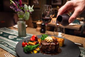 a person is pouring wine into a plate of food at Romantik Hotel Schweizerhof in Grindelwald