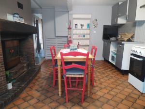 a kitchen with a table with red chairs and a fireplace at Le Nichoir de Lesmont in Lesmont