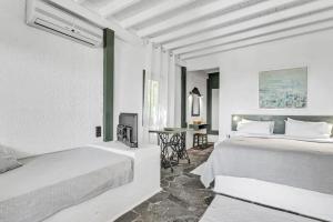 a white bedroom with two beds and a table at Niriides Beachfront Resort in Gythio
