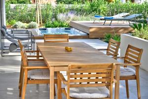 a wooden table and chairs on a patio with a pool at Jadrija Luxury Vacations Apt1 in Šibenik