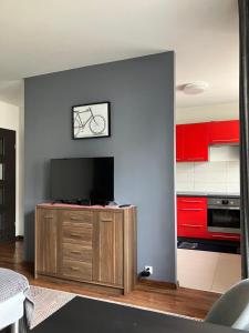 a kitchen with red cabinets and a flat screen tv at Szybowników 2 in Piła