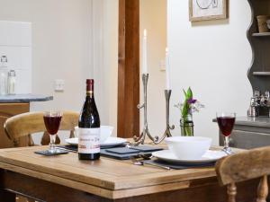 a bottle of wine on a wooden table with glasses of wine at The Nook in Amroth