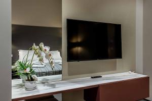 a room with a tv and a table with flowers at Salina Luxury Suites in Parma