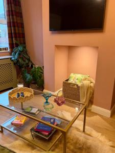 a living room with a glass table and a fireplace at Unique Vicarage Town Cottage in Leominster