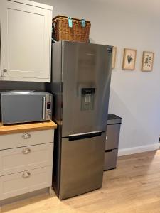 a stainless steel refrigerator in a kitchen with a microwave at Unique Vicarage Town Cottage in Leominster +14 photos