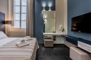 a hotel room with a bed and a sink and a tv at Salina Luxury Suites in Parma