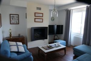 a living room with a blue couch and a tv at La Maison d'Adonis à la mer in Crozon