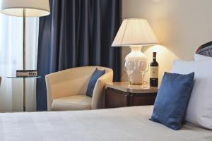 a hotel room with a bed and a chair and a lamp at Booking Hotel & Spa in Krakow