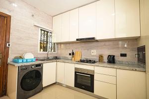 a kitchen with white cabinets and a washing machine at Ocean View Lekki Ikate in Alaguntan