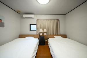 a bedroom with two beds and a window and two lamps at 囲宿-Kakomiyado- in Eiheiji