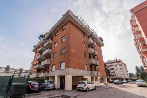 a tall brick building with cars parked in a parking lot at Monolocale Giulio Cesare in Novara