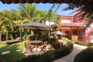 a patio with a table and chairs and an umbrella at La Dolce Vita Flat & Pousada in Praia do Frances