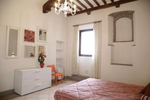 um quarto com uma cama, uma cómoda e uma janela em Il Capitello em San Gimignano