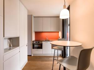 a kitchen with white cabinets and a table and chairs at b20 - serviced apartments bern ag in Bern