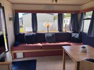 a living room with a couch in front of a window at 6 berth static in Skegness in Chapel Saint Leonards