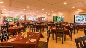 a restaurant with brown tables and chairs and windows at Silver Oak Resort in Rājankunti