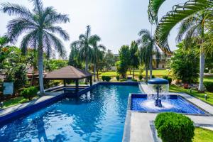 a swimming pool with a fountain and palm trees at Silver Oak Resort in Rājankunti
