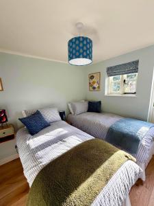 a bedroom with two beds and a pendant light at Orchard Barn next to Bewl Reservoir, Ticehurst in Ticehurst
