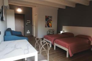 a room with two beds and a table and a couch at Montecarlo B&B in Tortona