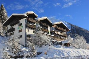 un grand bâtiment dans la neige avec des arbres enneigés dans l'établissement Hotel Jägerhof, à San Leonardo in Passiria