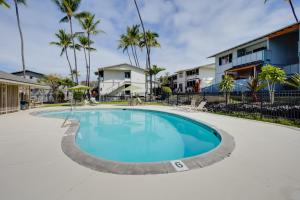 a swimming pool at a resort with palm trees at Lanai & Community Pool Access: Sunny Central Condo in Kailua-Kona