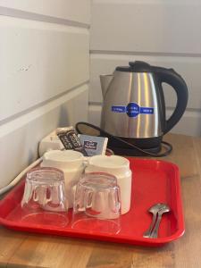 a red tray with utensils and a tea kettle at Kartano Kievari in Äänekoski