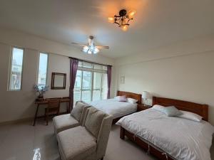 a bedroom with two beds and a chair and a ceiling fan at Emerald Grange in Gongguan
