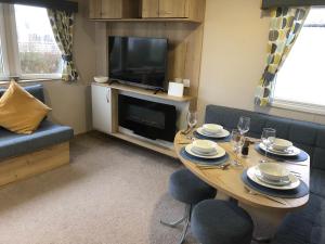 a living room with a table and a television at Dunes Escape in Lossiemouth